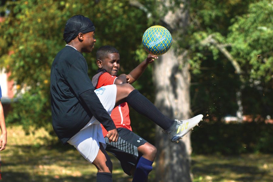 A photo of two boys kicking a soccer ball.