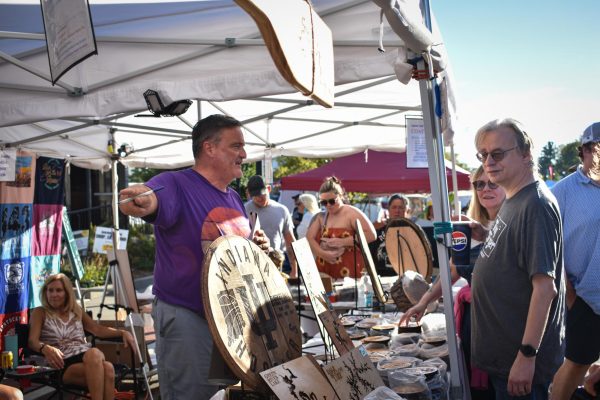 The Customer's Always Right: Geoff Webb, 59, directs a customer to view other products at his wood burning and carving vendor on Sept. 14 at Gaslight Festival Weekend. Photo by Loren Williamson.