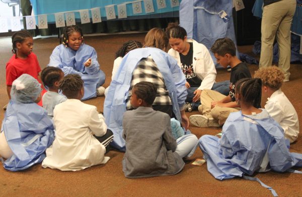 A group of young Future Healers members gather around a UofL medical student at a Future Healers workshop on September 14, 2024. 