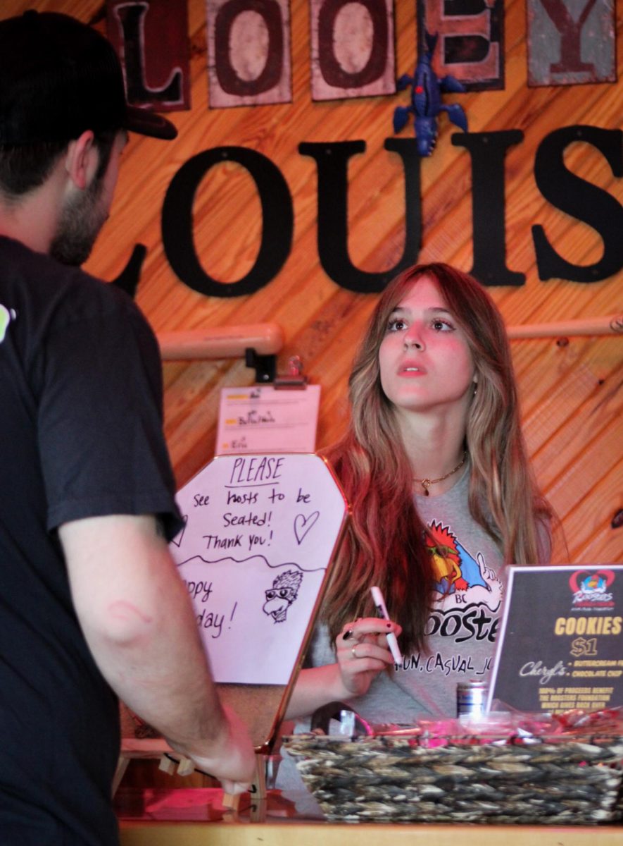 What Can I Get for You? - Ava Smith, 17, a junior at
duPont Manual High School, helps a customer at Roosters on Bardstown Road on April 17. “At Roost-
ers, you have a lot of regulars, so you have to be able to get to know people and remember orders,”
Smith said.